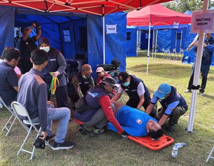 In a training scenario, an injured person is rescued. Participants in the training watch.