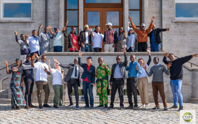 Eine Gruppe von Personen posiert für das Foto vor einem Eingang eines Gebäudes auf einem zweiseitigen Treppenabsatz.