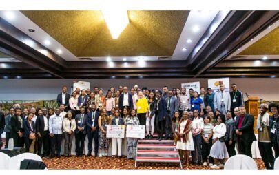 Conference participants gather on a stage and pose together for a group photo.