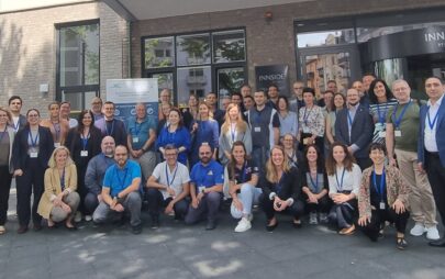 Eine Gruppe von lächelnden Personen posiert für das Foto vor dem Eingang eines Gebäudes. In der letzten Reihe der Gruppe steht ein Banner des Robert Koch-Instituts.