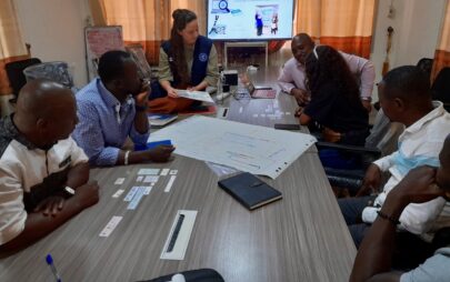 Eine Gruppen von Personen sitzt an einem Seminartisch, auf welchem ein beschriebenes Flipchart-Papier liegt.