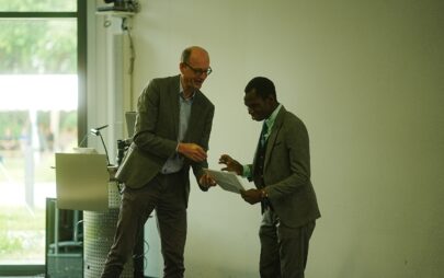 Zwei Männer in formalen Anzügen überreichen sich gegenseitig ein Dokument