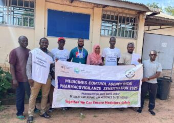 Eine Gruppe von Personen steht vor einem Gebäude und hält ein Banner mit Aufschrift: "Medicines Control Agency - Pharmacovigilance Sensitizateion 2025""